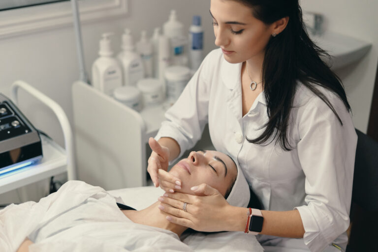 Una profesional de la salud estética aplica un tratamiento facial a una paciente en una clínica, demostrando las técnicas prácticas que se aprenden al estudiar dermocosmética para el cuidado especializado de la piel.